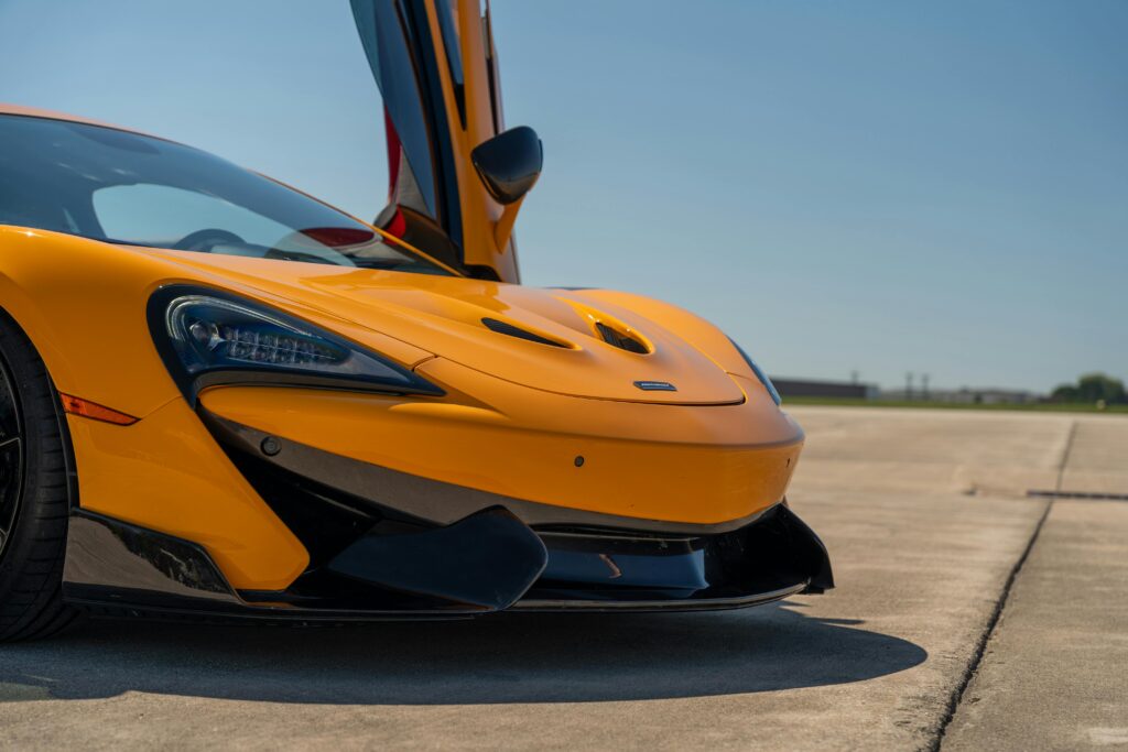 Striking orange McLaren sports car with doors open, captured on a sunny day in Illinois.