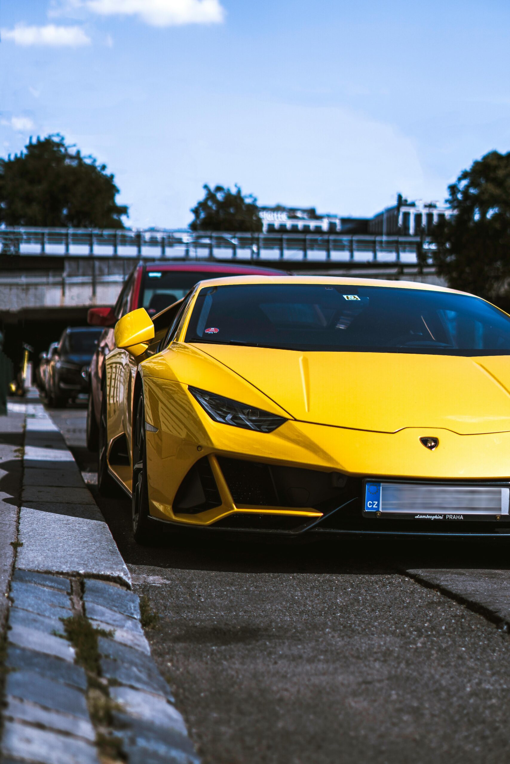 A vibrant yellow Lamborghini hypercar parked outdoors on a city road during the day.